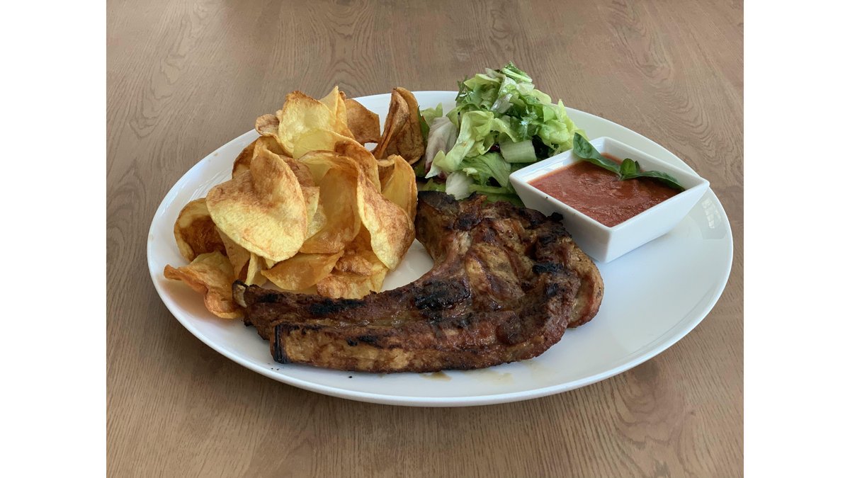 Tomahawk de porc la grătar cu chips-uri de cartofi și mix de salată cu roșii cherry