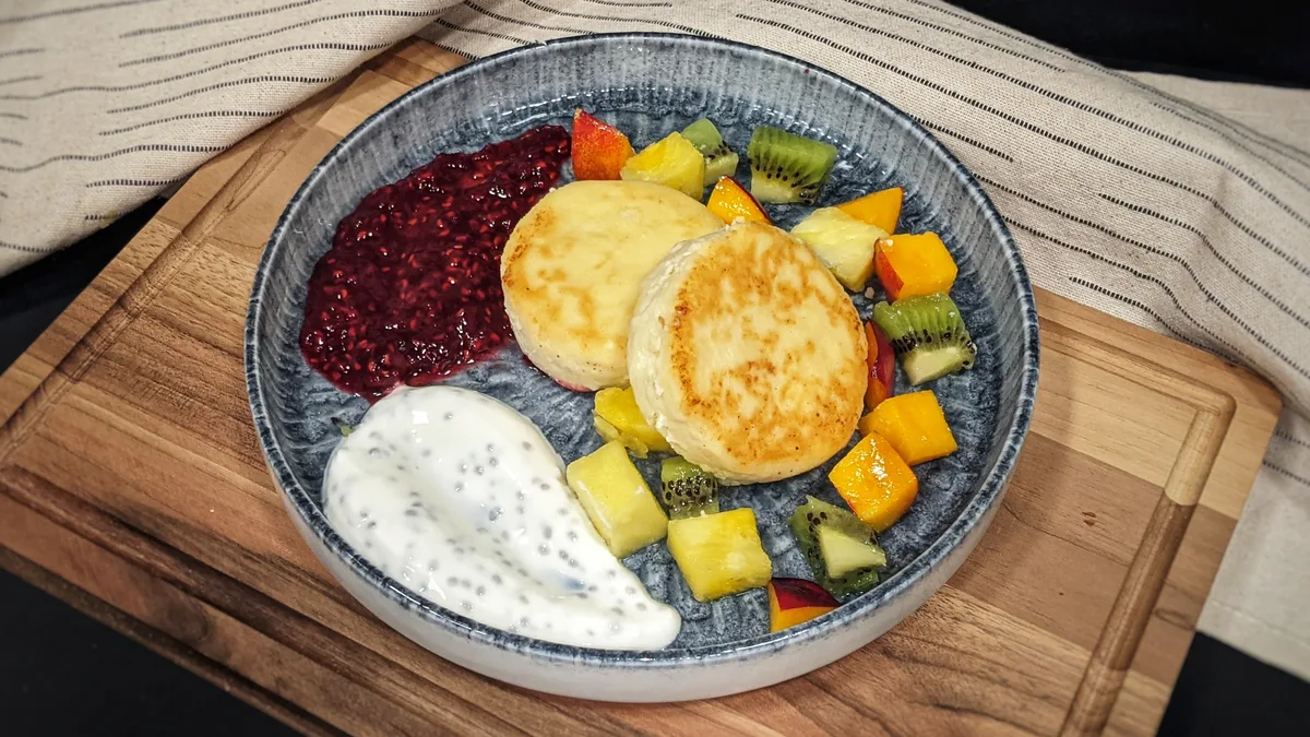 Cottage cheese syrniki with fresh fruits and sour cream with chia seeds